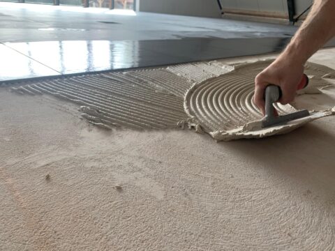 Tegelzetter smeert Coba CTA 120 tegellijm uit op de ondergrond, vocht- en vorstbestendig voor professioneel tegelwerk.